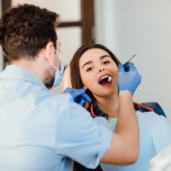 dentist-making-professional-teeth-cleaning-withb-cotton-female-young-patient-dental-office